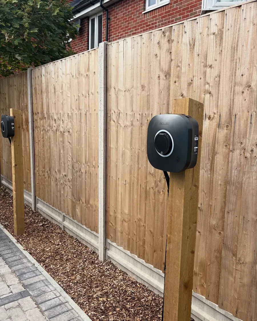 Wall-mounted EV charger installed on a garden fence post
