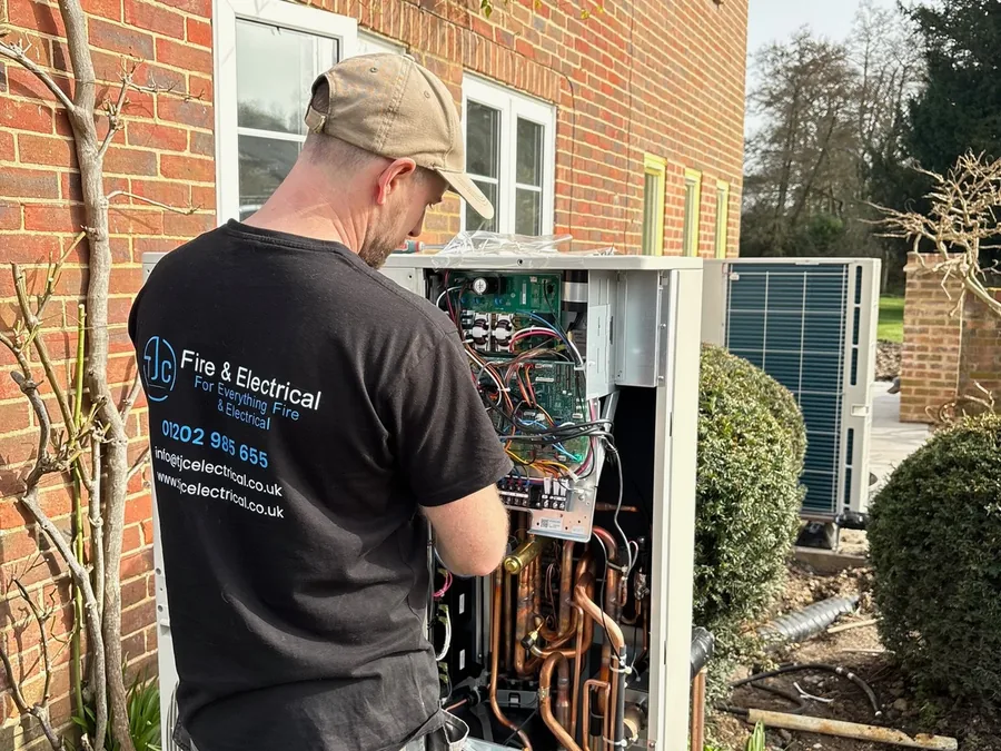 TJC engineer working inside the control panel of an air source heat pump