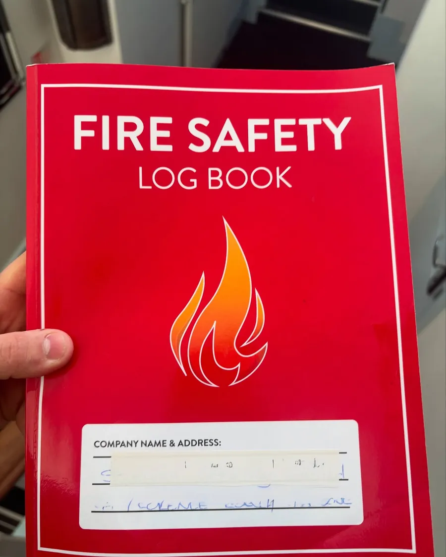 Red fire safety log book held in hand