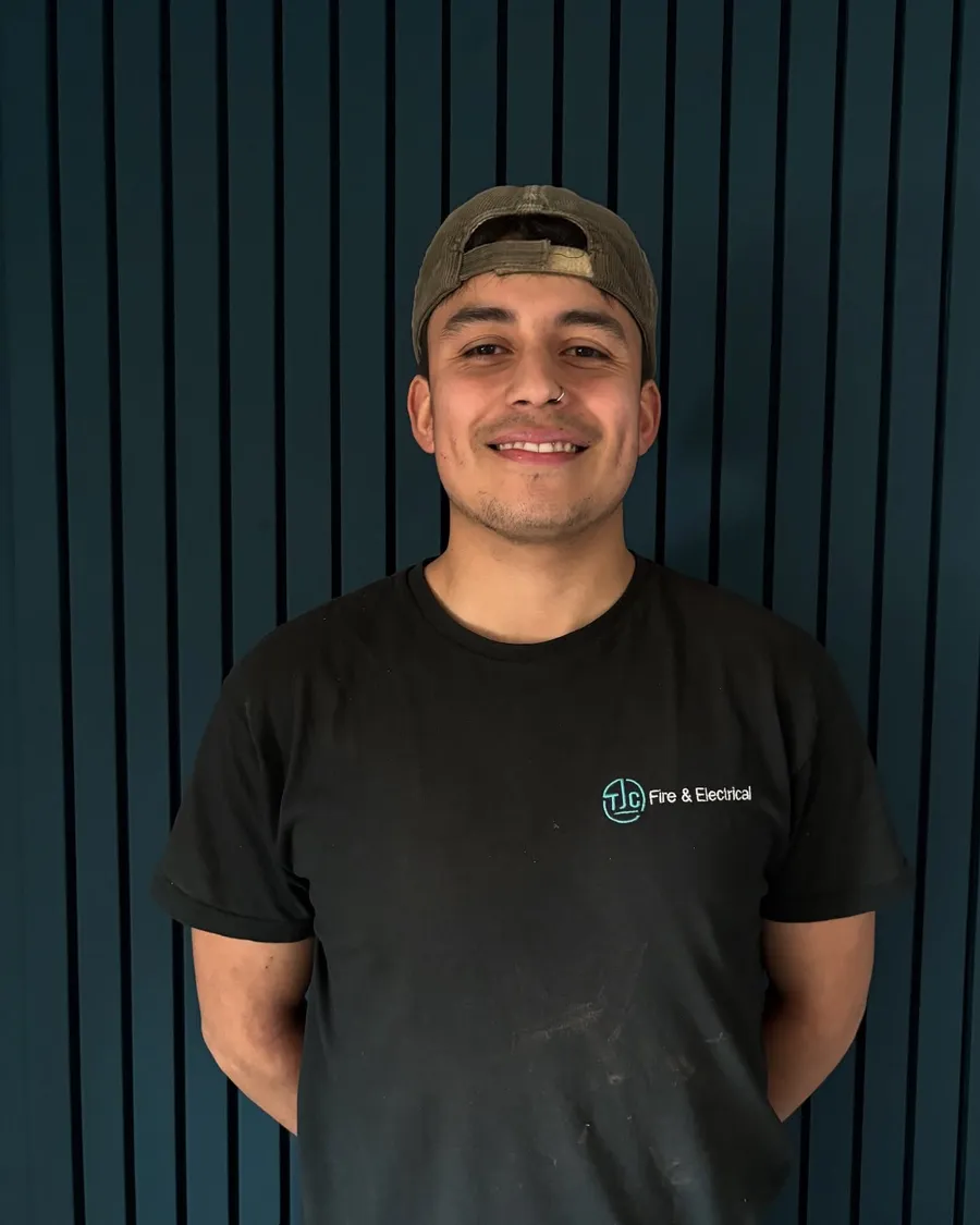 Alex in TJC branded workwear against a slatted wall