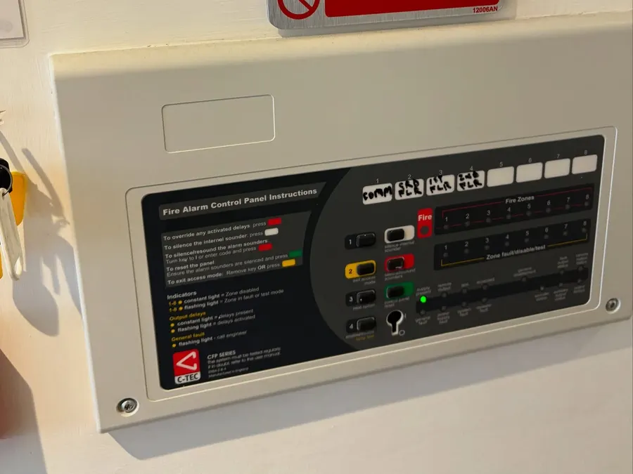 Fire Action notice above a fire alarm control panel with labelled zones
