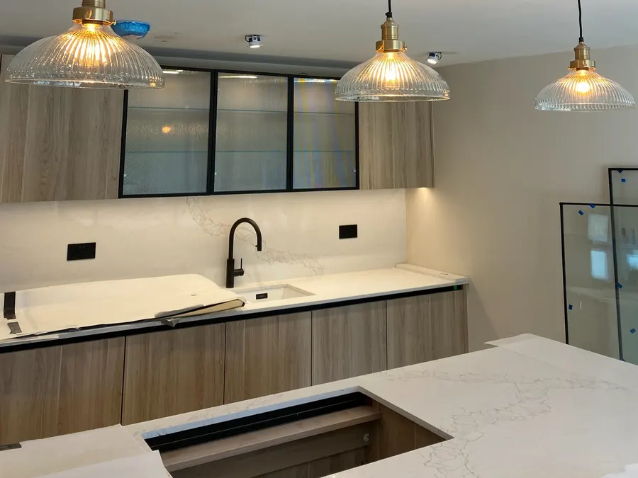 Three ribbed-glass brass pendants over a kitchen island