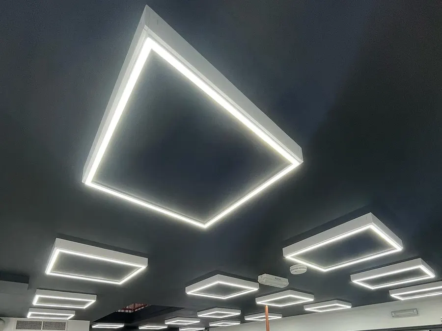 Commercial space lit by rectangular LED perimeter fittings on a dark ceiling