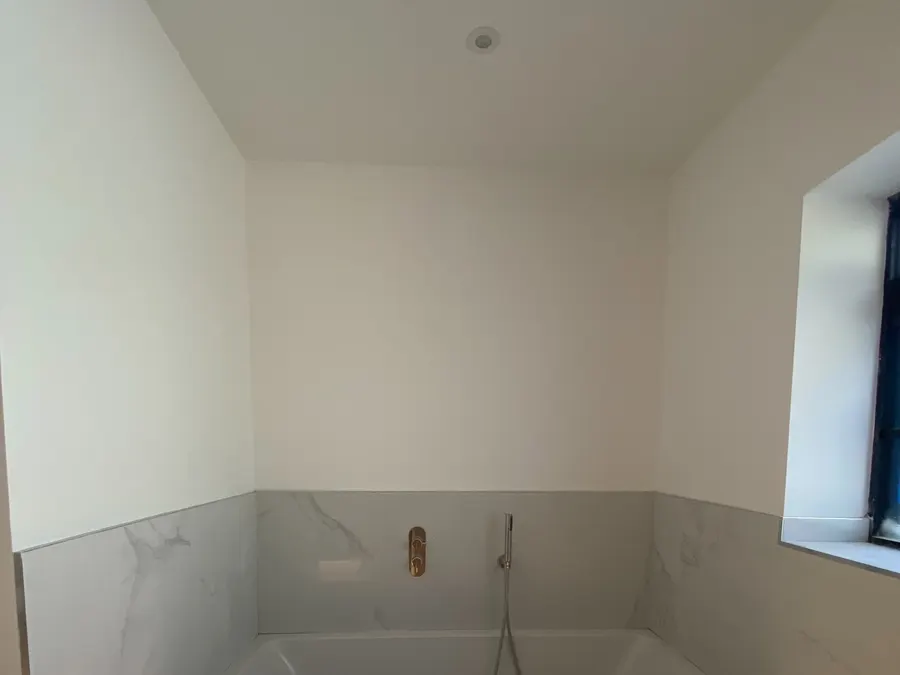 Bathroom with an LED strip washing the floor beneath a tiled bath