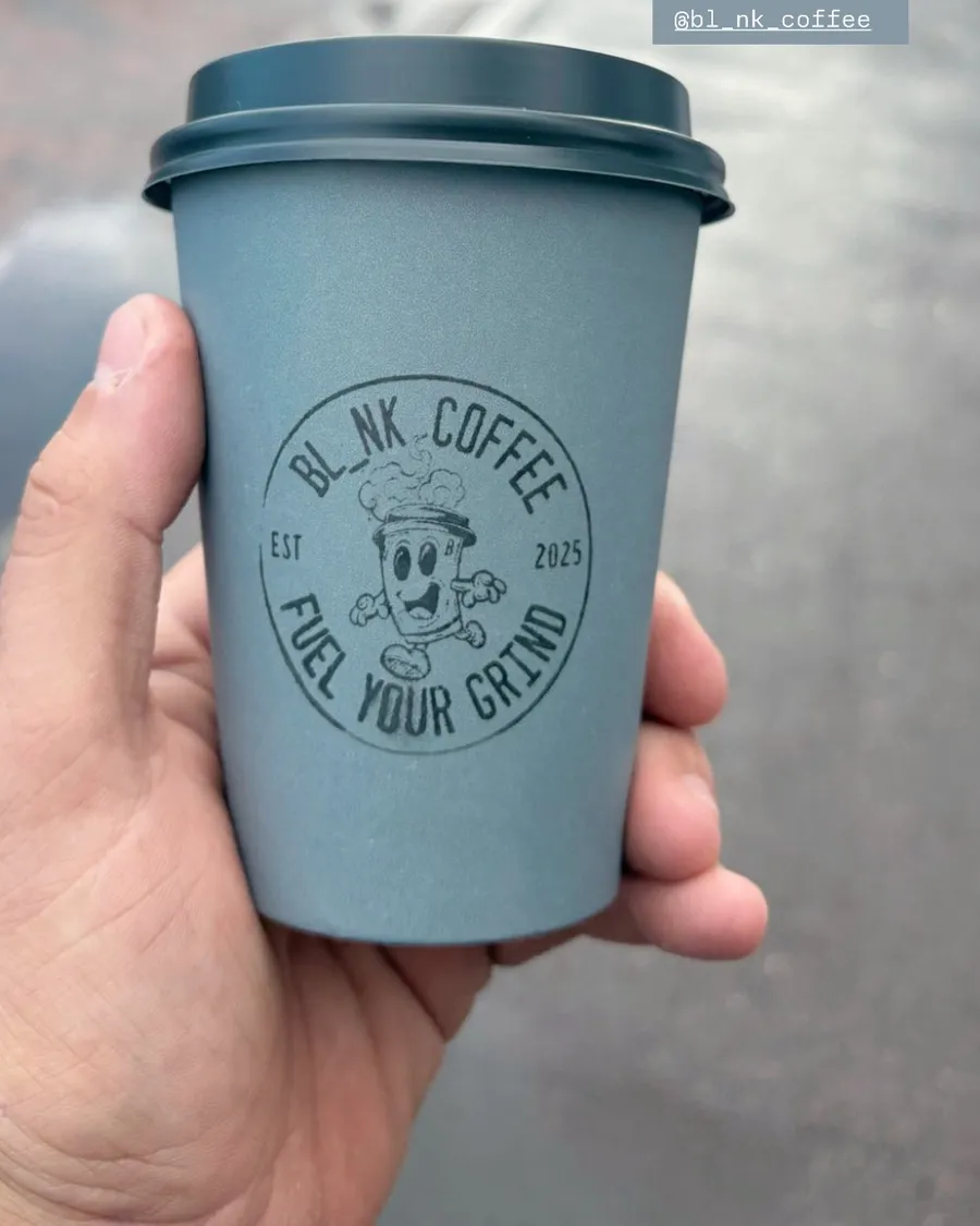 Hand holding a BL_NK COFFEE branded takeaway cup