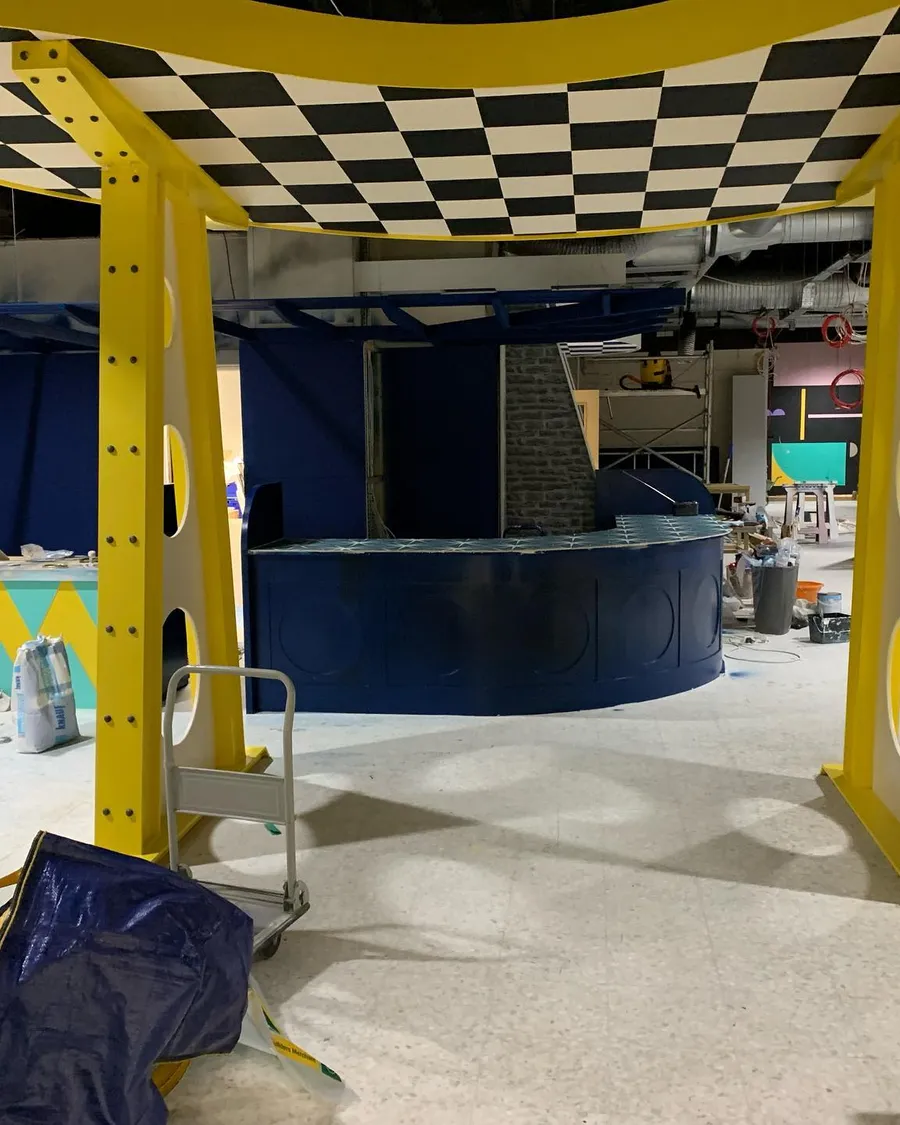 Indoor skatepark interior with yellow steel frame and checkerboard ceiling